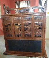 Front view of chest showing carved panels and upper decorative rail