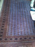 Full view of purple and brown rug laid flat on concrete