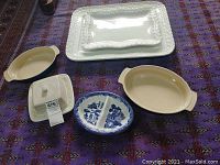 Photo showing all six ceramic serving dishes and trays arranged on a purple patterned surface.