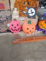 Photo showing various Halloween decorations including the pink pumpkin with snow globe, orange pumpkin, and Trick or Treat sign on the floor.