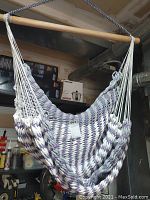 Front view of the woven purple, white, and silver hammock chair hanging from the wooden spreader bar.