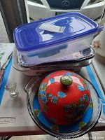 All kitchenware items stacked together including plastic containers, aluminum pans, Corning Ware baking dish and serving dish with lid