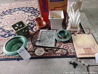 Photo of all items including white ceramic piece, two plaques, pots, and hanging hooks on carpet.