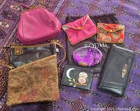 Full lot including purses, wallets, change purse, and jewelry bags on patterned cloth.