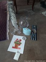Overview of various vases including tall white ceramic vase with bird pattern, multiple small glass vases, blue ceramic vase, oval mirror wall decor, and an art print with potted flowers on floor