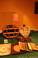 Photo showing two shadow boxes (octagonal wooden and heart-shaped white), grapevine wreath frames, coiled grapevine wreaths, assorted wooden picture frames, pine brooms, and burlap canvas package