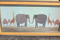 Full image of the framed folk art print showing elephants, giraffes, camels, and tortoises on a grassy plain with pale blue sky background.