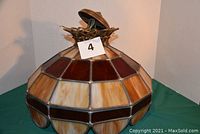 Ceiling lamp shown from the side displaying stained glass shade with amber and burgundy sections.