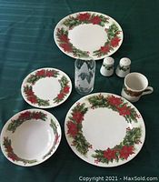 Photo showing a selection of Christmas-themed dinnerware including a large serving platter, dinner plate, soup bowl, dessert plate, cup, salt and pepper shakers, and a Christmas etched glass.
