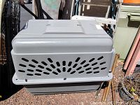 Side and top view of plastic dog crate showing ventilation holes and general used condition.