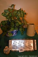 Shows all four items: blue and white crock with artificial green plants, beige ceramic pitcher, small hand-painted pottery vase, and aluminum serving tray with embossed floral design