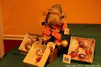 Full lot showing stuffed Santa doll sitting behind boxes containing handcrafted birds, balls, and ceramic bells.