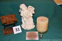 Angel figurine, wooden school desk music box, aromatic candle, instruction card, and batteries shown together