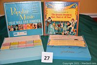 Two vinyl box sets displayed on green cloth; left box is Reader's Digest Popular Music That Will Live Forever with 10 albums; right box is Longines Symphonette The Greatest Broadway Show Music of All Time with 8 albums