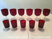 Eleven pieces of red glass stemware arranged on a white surface, showing 6 tall stemmed glasses and 5 low stemmed glasses.
