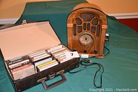 Full lot showing the Thomas radio and cassette player next to a faux leather case holding multiple cassette tapes, with power cord visible.