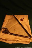 Image showing left side car wing window with metal frame and triangular glass, laid on cloth along with vintage Chevrolet key ring.