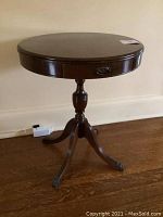 Full view of the drum table showing the round top, single drawer, turned pedestal, and tripod base with claw feet.