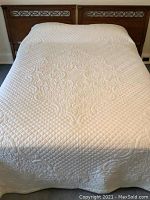 Full view of cream quilt laid on bed showing size and coverage