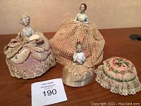 Lot of three antique art deco pin cushion dolls and fabric pin cushion showing full grouping and scale.