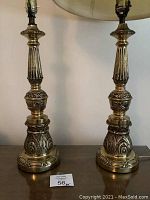 Pair of tall vintage brass lamps side by side, showing full height and detailed carved design