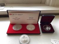 Four round RCM coins and medallions in display: two in leatherette case, one loose in capsule, one in small velvet box
