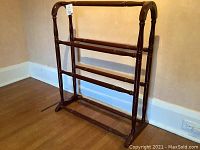 Full side-angle view of the solid wood quilt rack showing its height, structure, and condition.