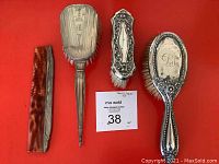 Full view of the four dressing set items including the folding comb, three brushes of varying design and size.