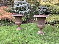 Two cast iron urn planters side by side on lawn