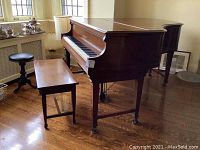 Grand piano, rectangular bench, and round stool in room