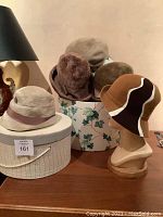 Group photo of five vintage hats arranged with two hat boxes and a mannequin displaying one hat.