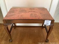 Front and side angled view of wooden bench with upholstered seat and carved legs.