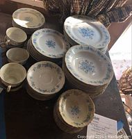 Top view of the dinner plates, smaller plates, and teacups showing blue floral pattern and scalloped edges.
