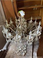 Overview photo showing the whole chandelier with multiple arms and some crystals broken on the ground.