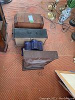 Four mantle clocks stacked showing tops and backs - wood and black finishes visible