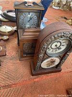 Photo of three clocks on an orange carpet, including two ornate mantle clocks and one rectangular wall clock