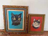 Two framed original cat paintings on stretched canvas. One is a black cat on bright blue; the other is a multicolored cat on red.