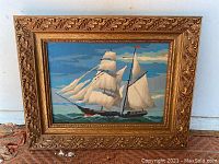 Front view of the framed maritime acrylic painting, showing the sailing ship with white sails and blue sky background, in an ornate gold frame.