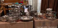 Full view of the silver plated service ware collection on boxes including baskets, bowls, ice bucket.
