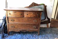 Front view of wooden dresser showing four drawers with ornate metal handles, dresser wood finish and carved bottom detail