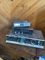 Full view of three stacked vintage audio components placed on a wooden dresser with wood panel wall background.