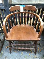 Front view of a wooden arm chair showing curved backrest with vertical spindles and contoured seat.