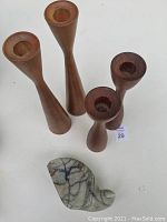Full lot overview showing all four teak candle holders and the carved stone bird on a white surface.