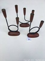 Set of three candle holders, two double and one triple, showing wood bases and black metal frames with wooden candle holders