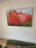 Frontal view of the large floral canvas artwork with vibrant red poppies and blue sky background hung on wall.