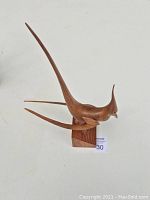 Full side view of the wooden cardinal bird sculpture showing its long tail, crest, and wooden base.