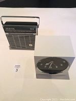 Both items side by side on a white background: Zenith portable radio and a white cube clock.