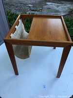 Full view of teak side table showing rectangular top, raised edges, and canvas sling insert