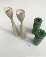 All four wooden candleholders, two white tall and two green shorter, arranged together showing size and style.