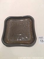 Top view of the square ceramic tray showing embossed female figure and garden scene in dark glaze.